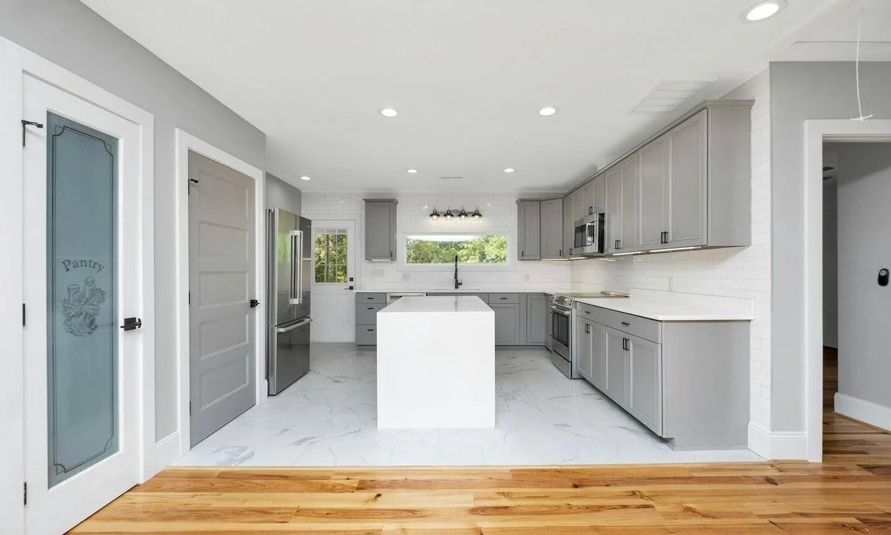 A finished kitchen with gray cabinets, white countertops and a central island.